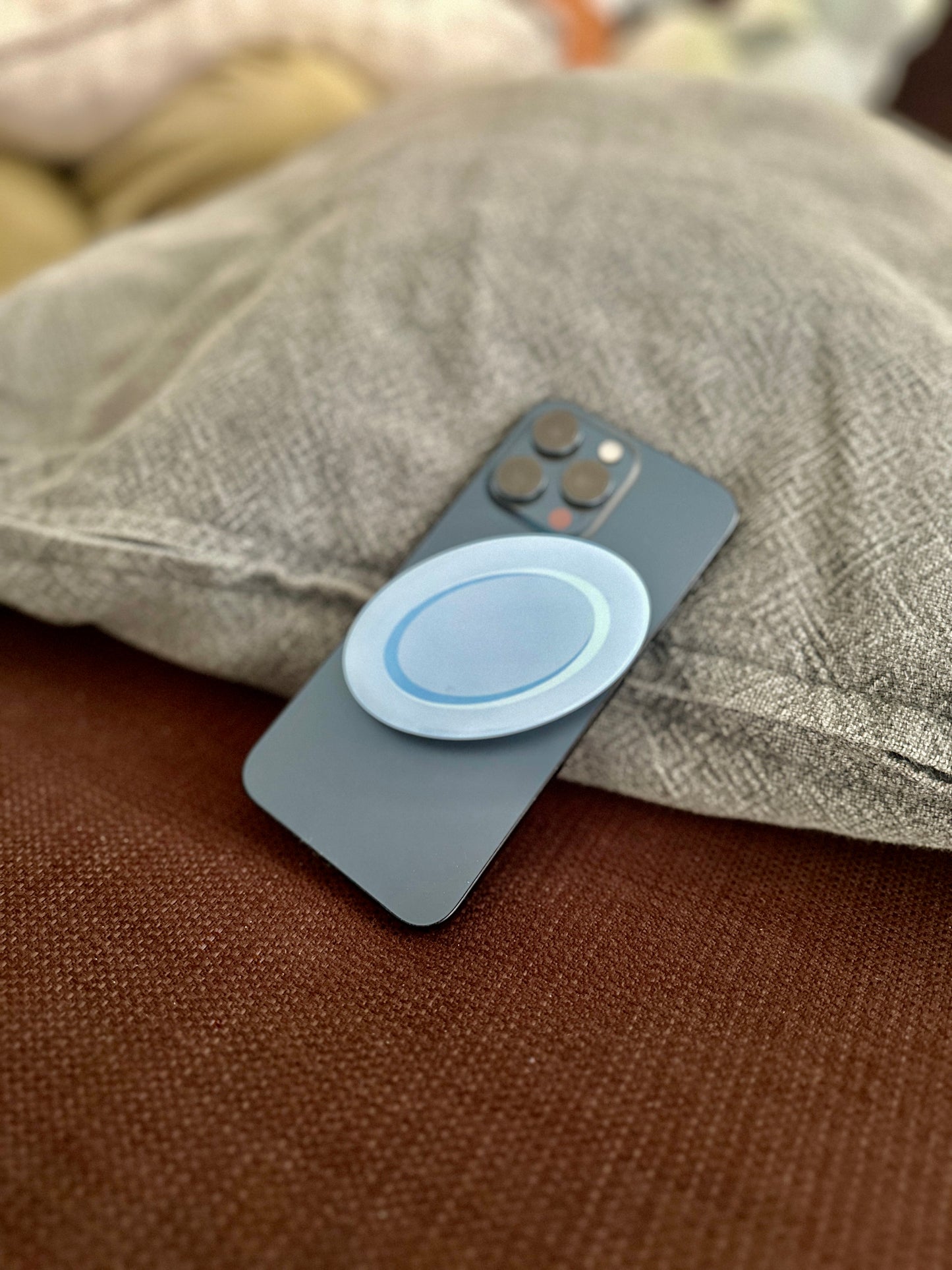 Phone with a blue plate pop socket on a textured surface