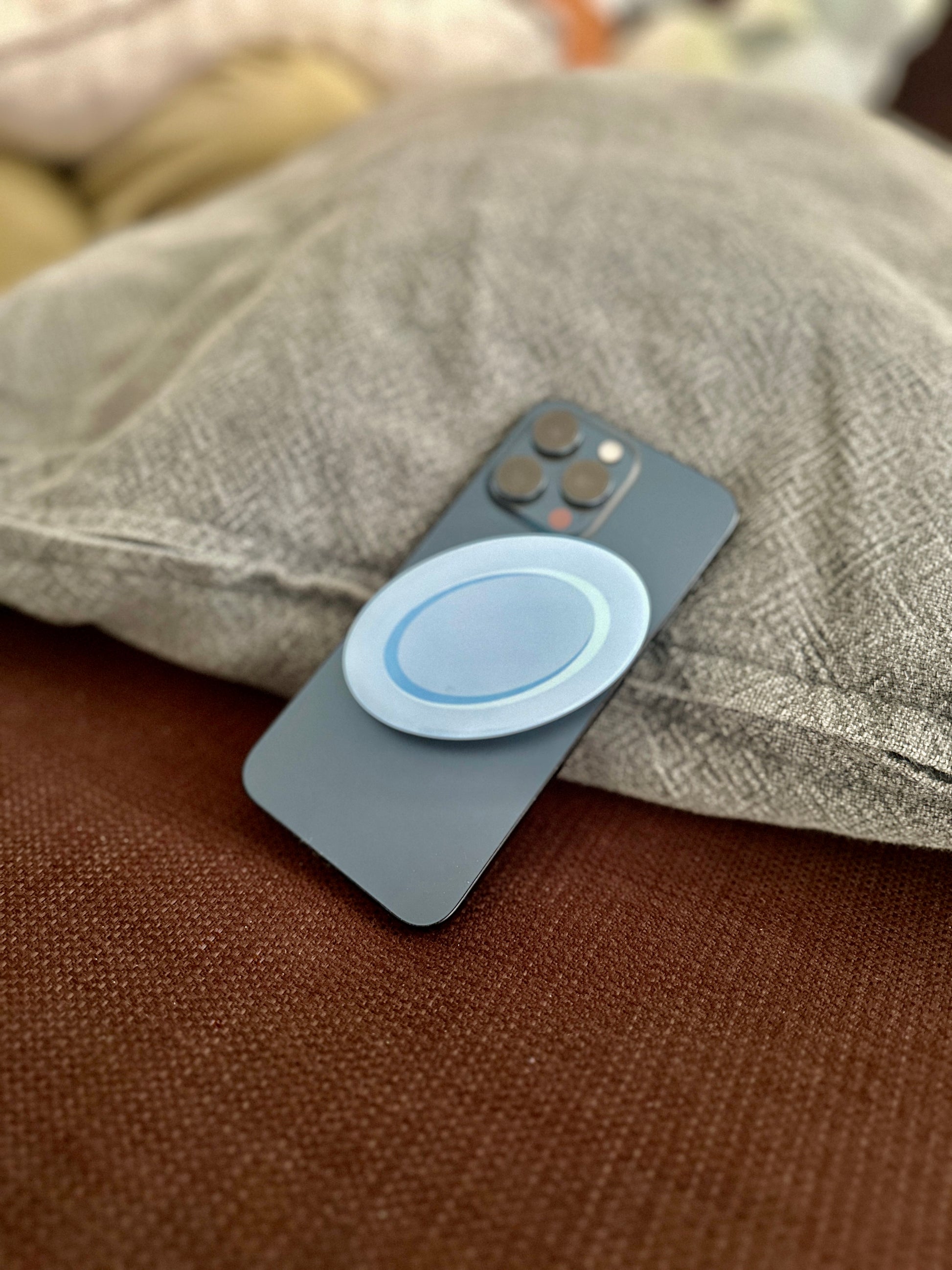 Phone with a blue plate pop socket on a textured surface