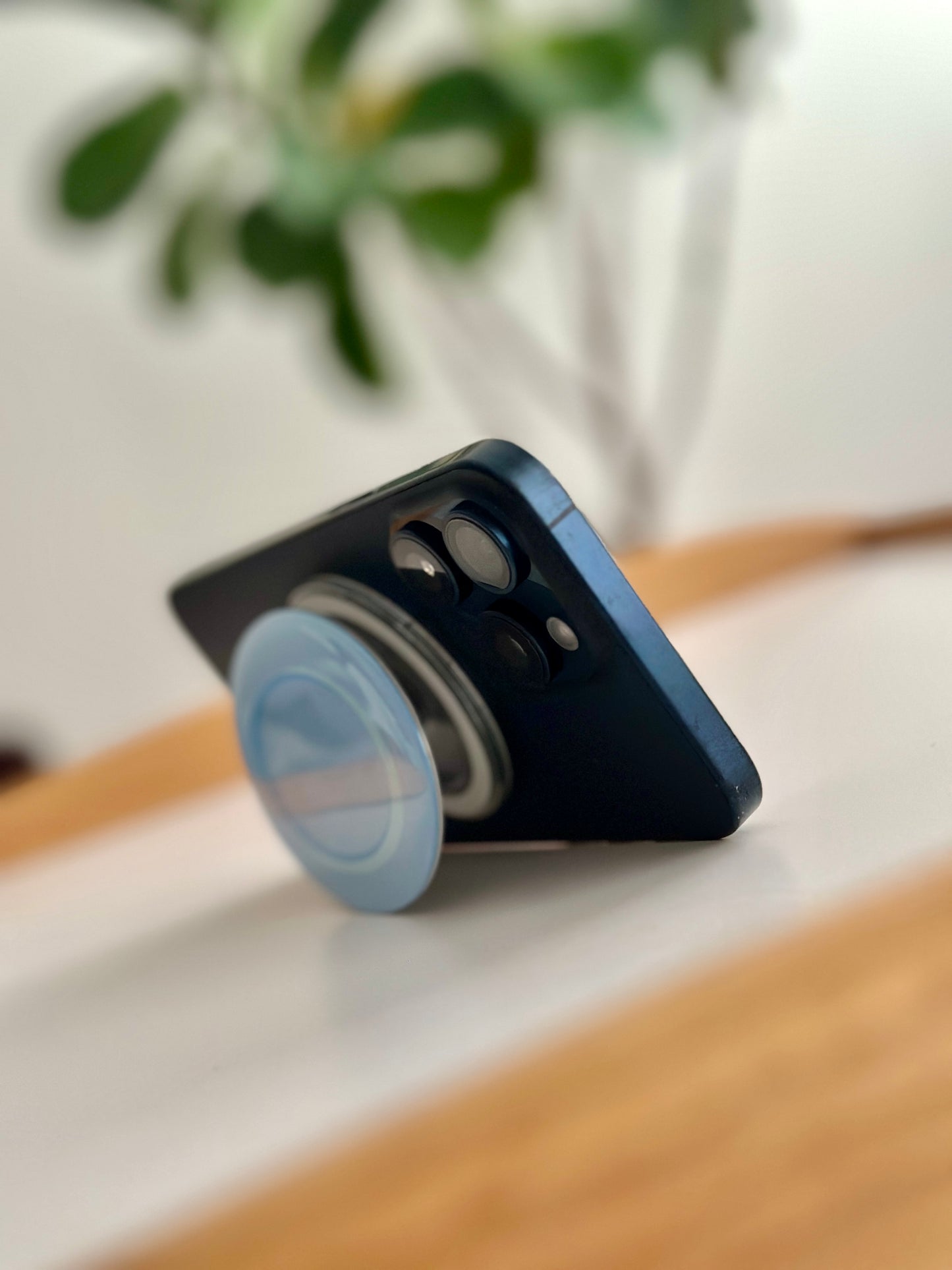 Phone case with a blue kopitiam plate pop socket on a surface with a blurred background